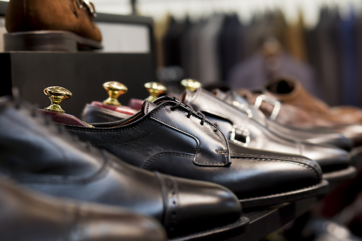 Hombre probándose varios zapatos de hombre elegantes y casuales, con diferentes estilos y colores sobre una mesa de madera